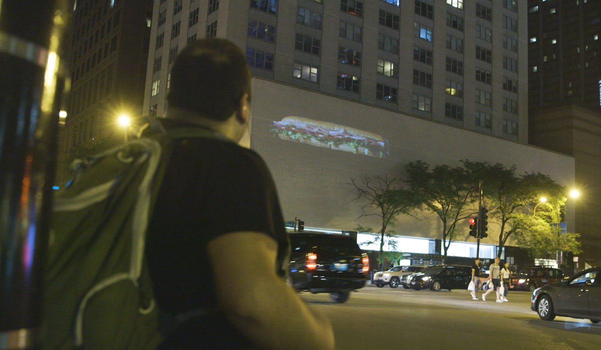 A Customer Looks At A Subway Sandwich On A Building