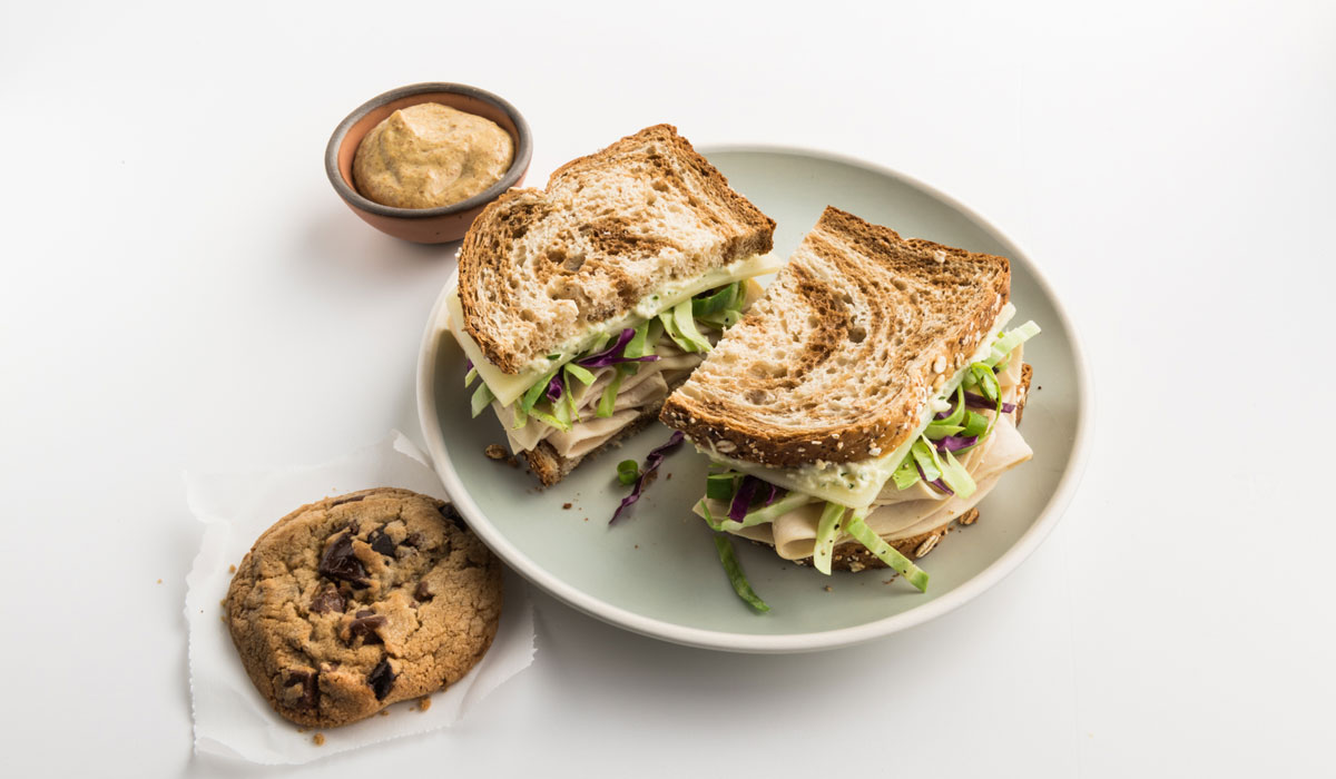 The Grüben: Zoës Signature Sandwich With Sliced Turkey, Manchego Cheese, Crunchy Mediterranean Slaw And Feta Spread Layered On Marble Wheat Bread, Served With A Zoës Chocolate Chip Cookie