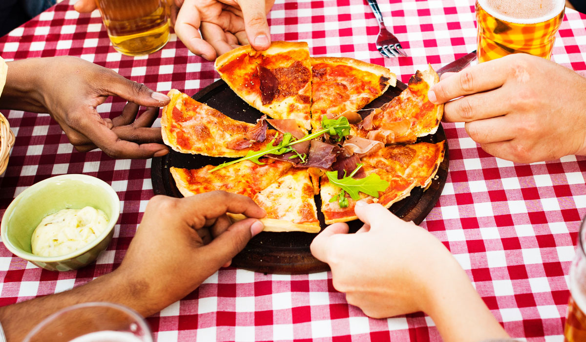 Diners Grabbing Pieces Of A Pizza Pie