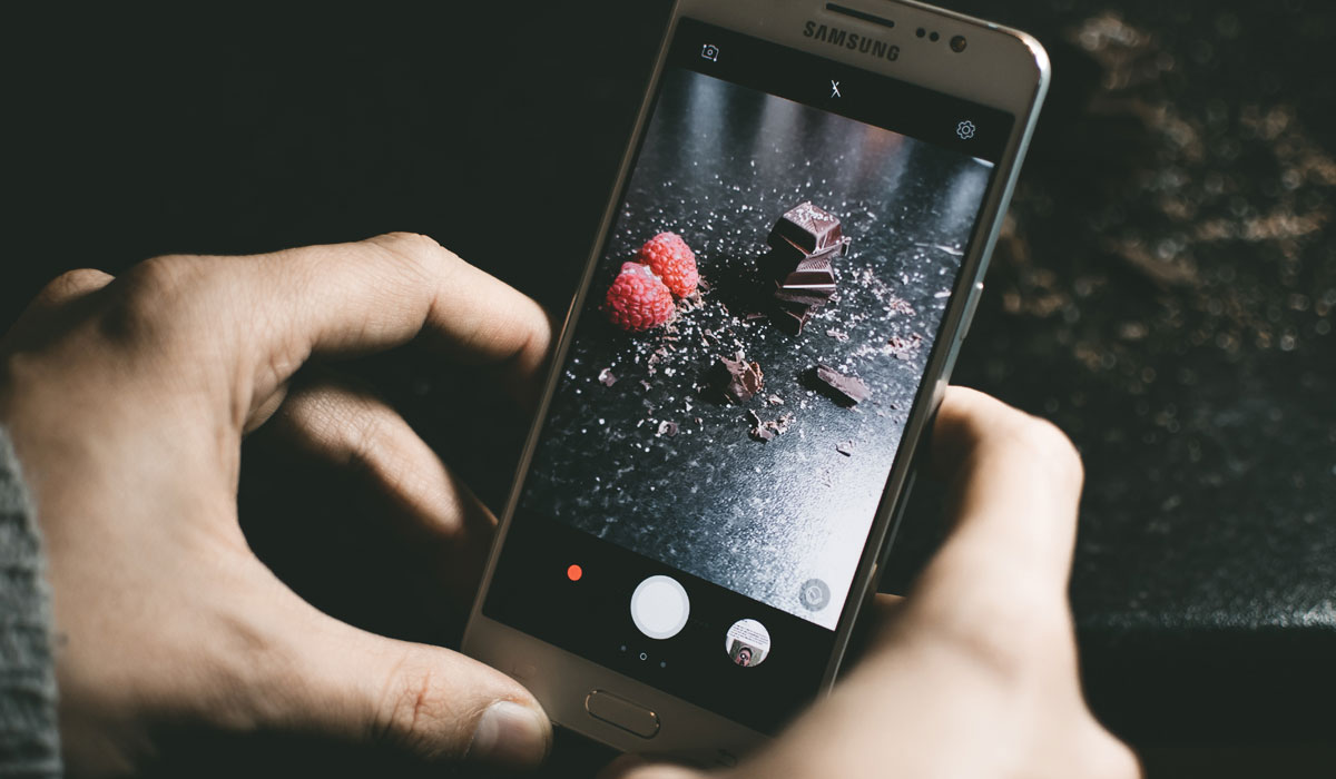 nearly-40-percent-dining-experiences-involve-smartphone A Customer Holds A Phone To Take A Picture Of Dessert