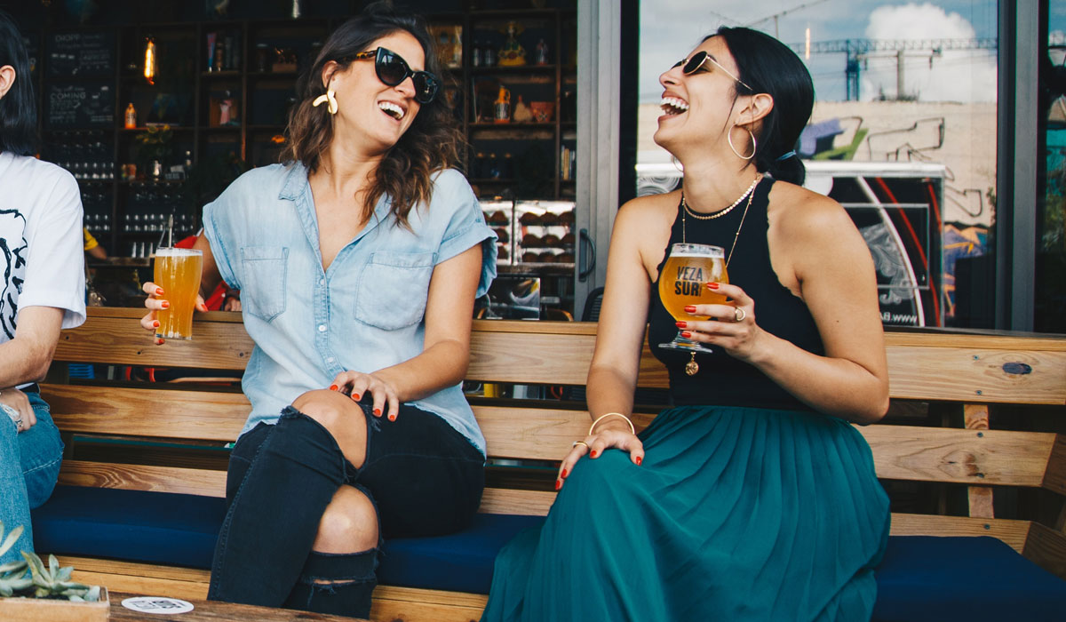 Two Women Drink Beer Outside A Restaurant