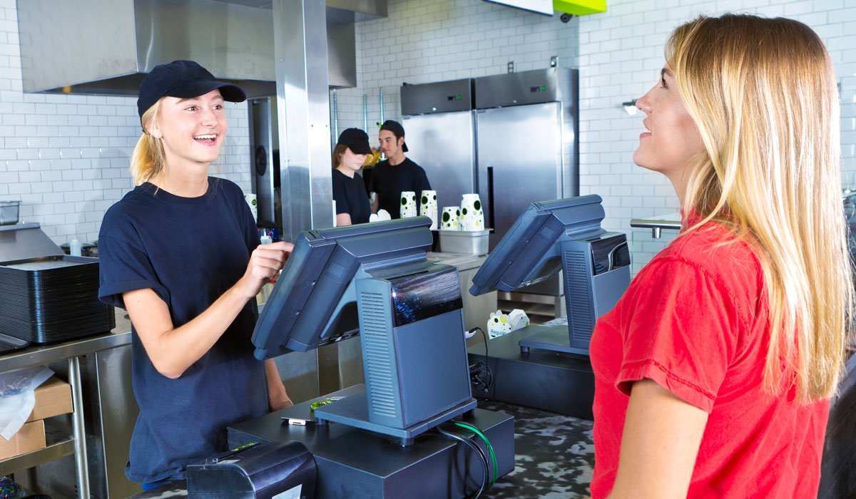 A Restaurant Employee At A Fast Food Register Helps A Customer