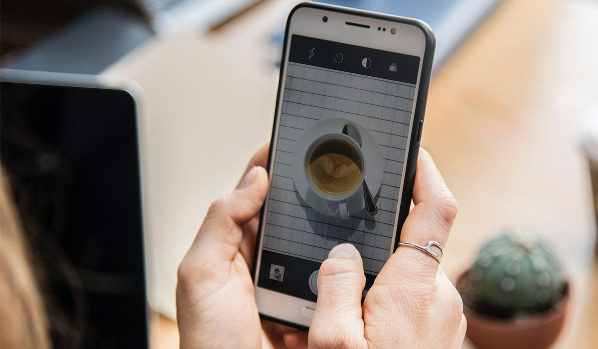 A Person Takes A Photo Of A Cup Of Coffee With Their Mobile Phone