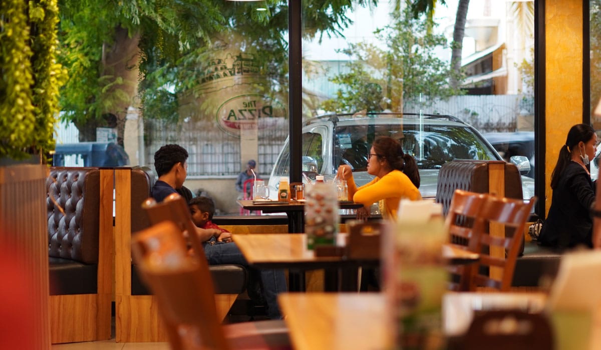 Guests Sit At A Table Inside A Restaurant