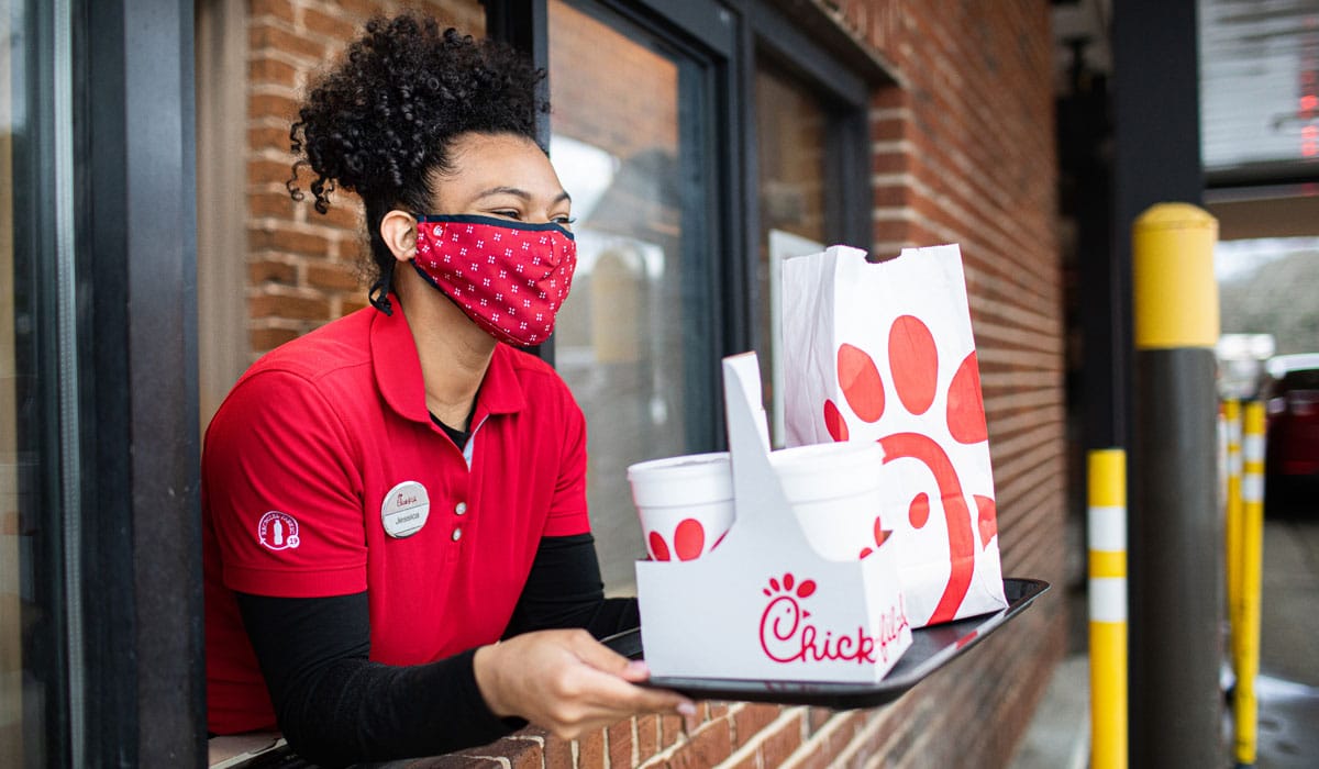 Chick Fil A Employee Handing Food Out The Window Of A Drive Thru