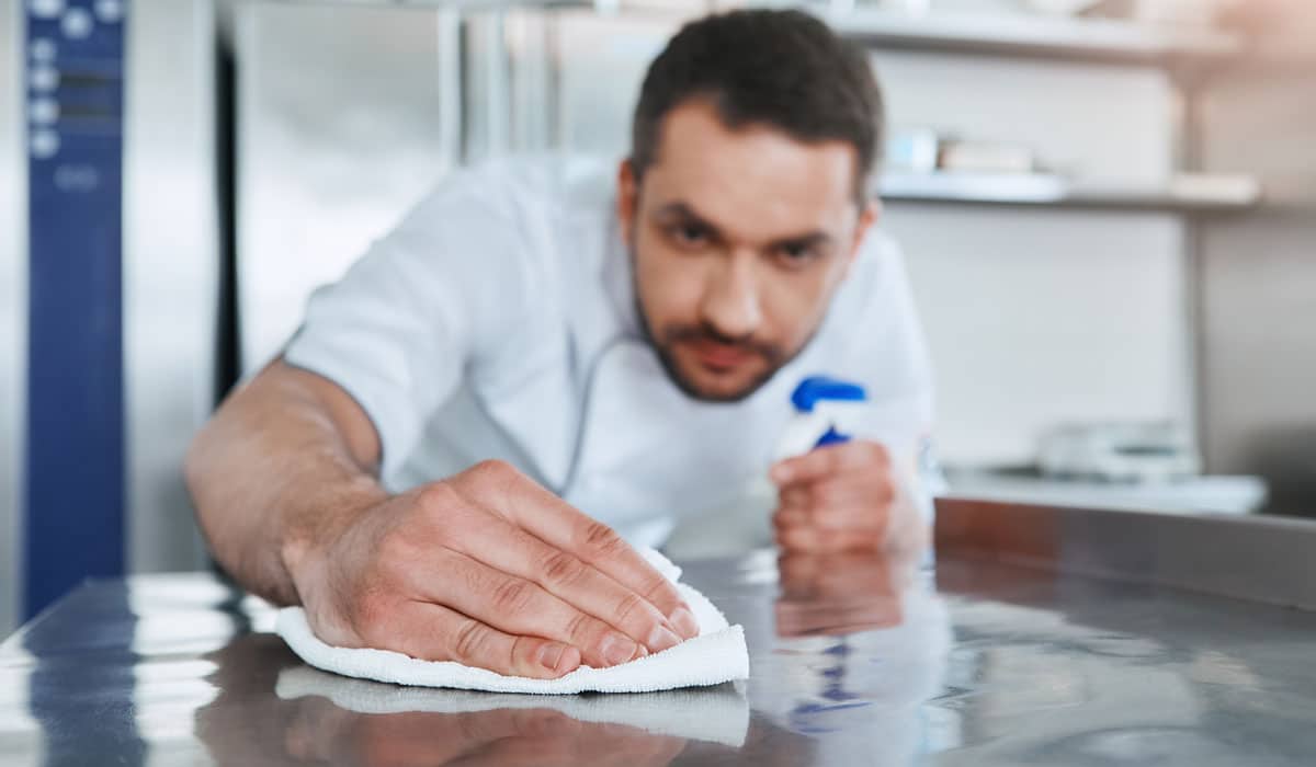 FoodSafety Worker In Restaurant Kitchen Cleaning Down After Service