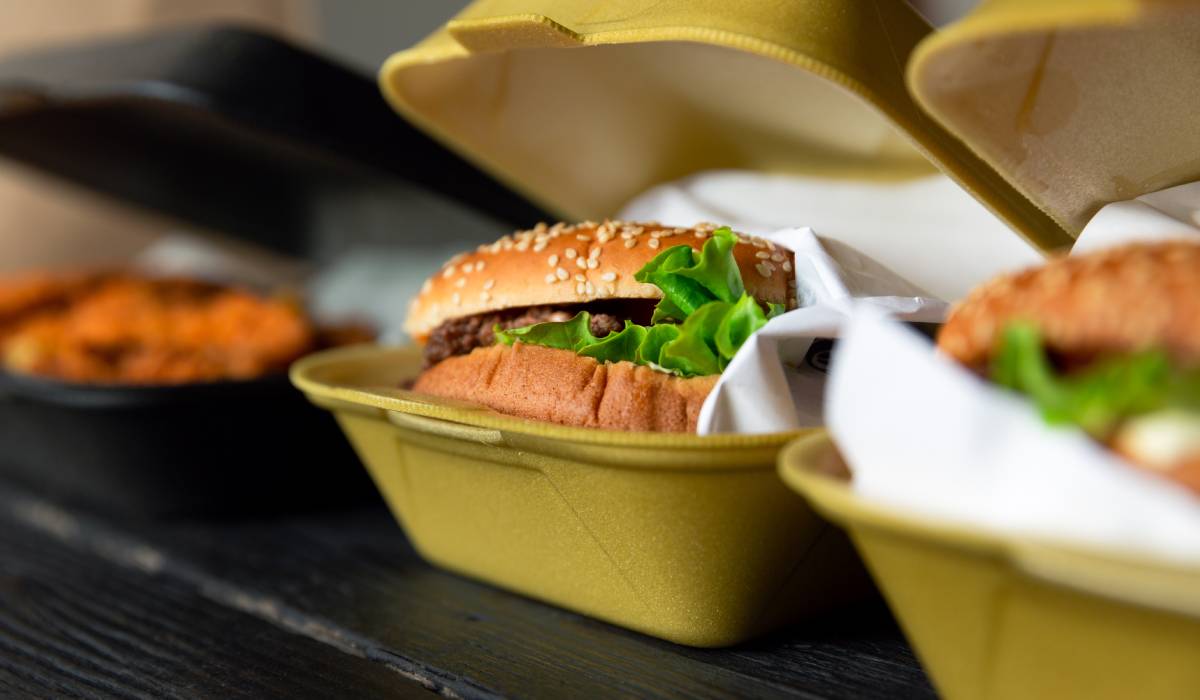 Hamburger In A Takeaway Container On The Wooden Background