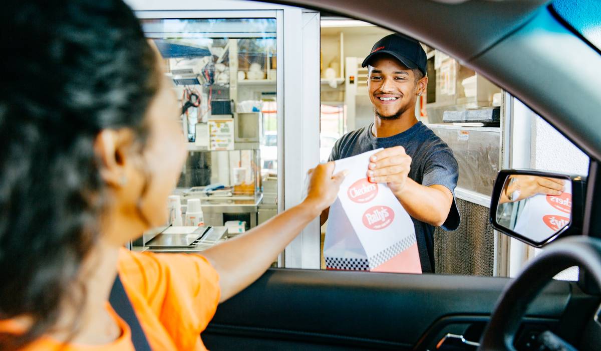 Customer grabs meal from drive-thru window.