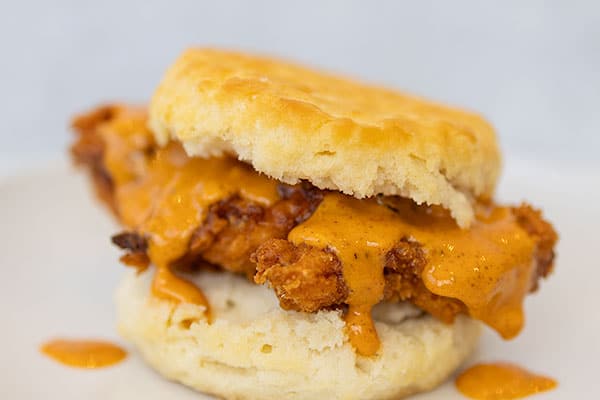 fried chicken sandwich with sauce and a biscuit bun.