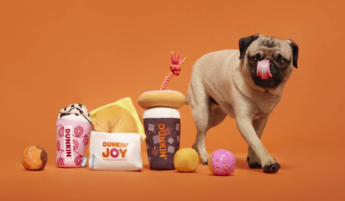 A dog beside some of Dunkin's dog toys.