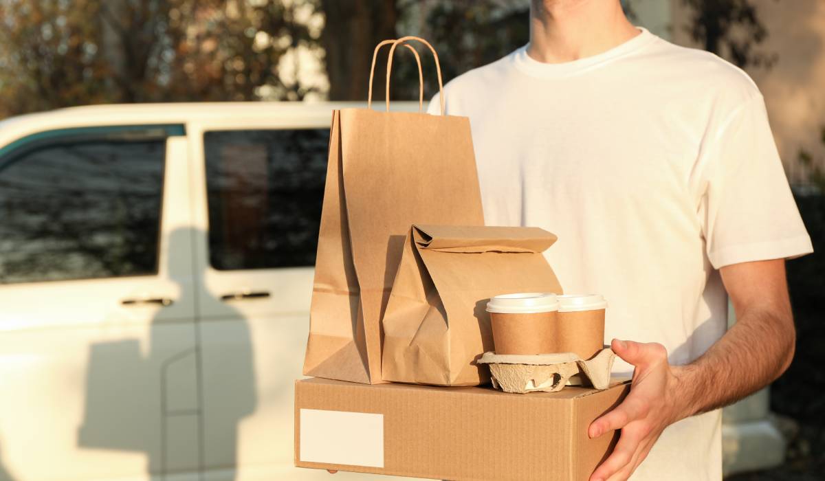 Person holding delivery food and drinks.