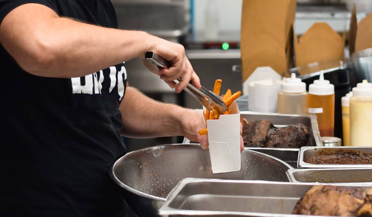 Fast-food worker putting fries in a basket.