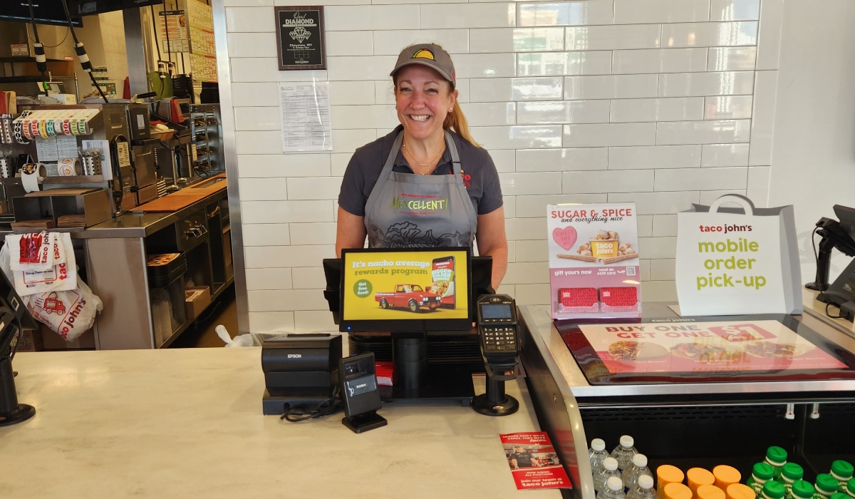 Taco John's CEO Heather Neary working as a cashier inside a restaurant.