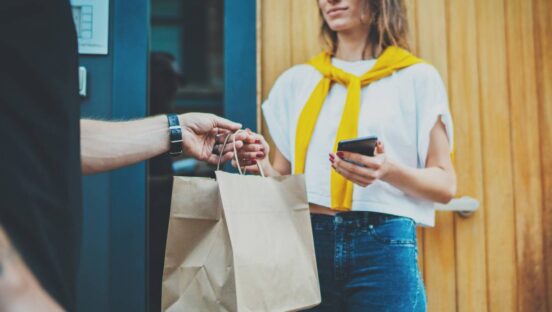 Delivery bag being handed to customer with a phone.