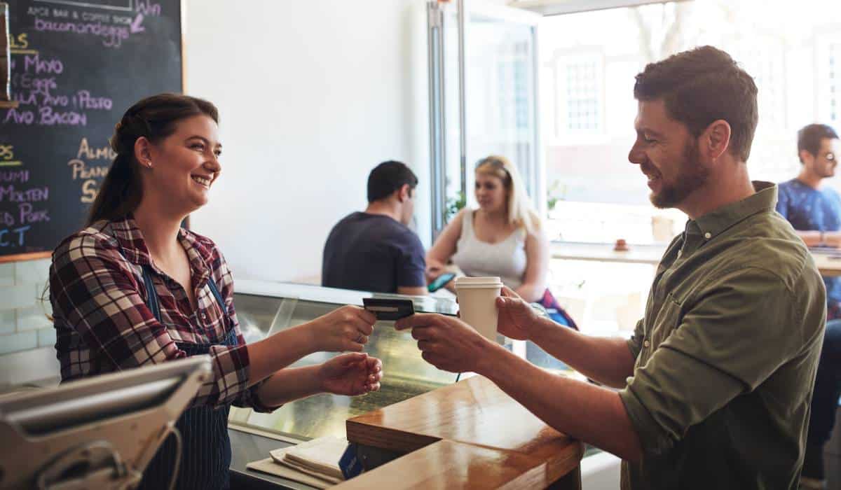 Restaurant customer handing card to cashier.