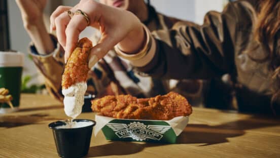 Customer dipping Wingstop chicken tenders into ranch.