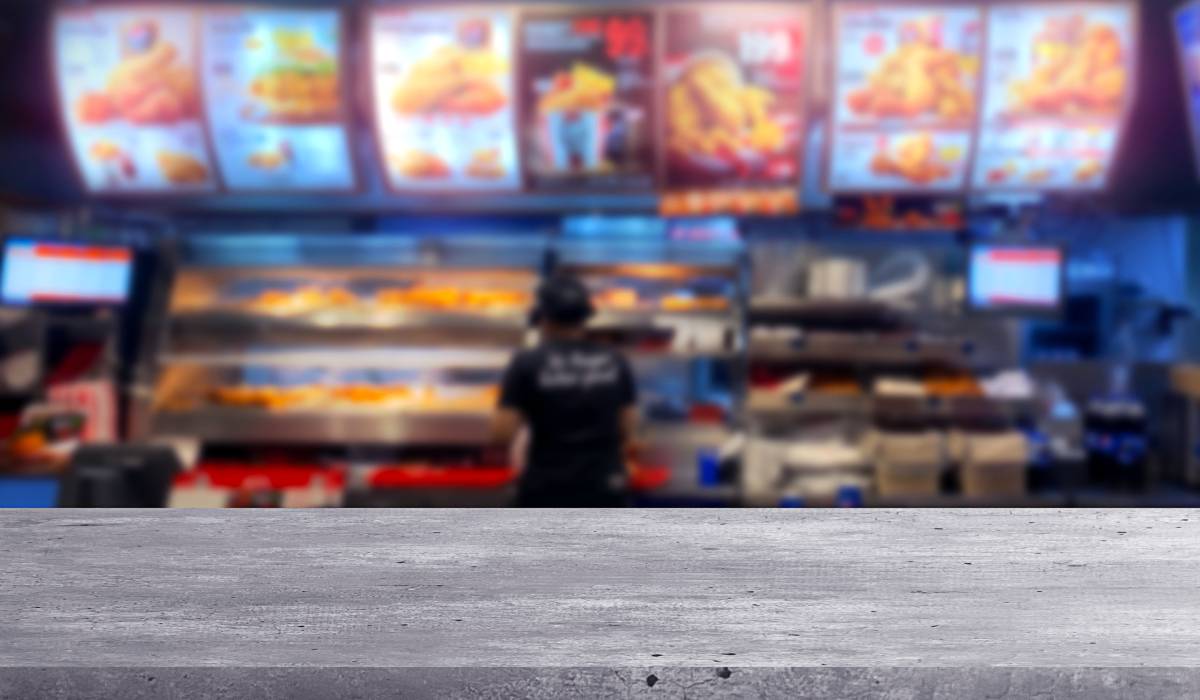 Modern wooden table with blurred fast food restaurant background.