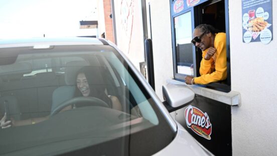 Snoop Dogg greeting a Raising Cane's customer at the drive-thru.
