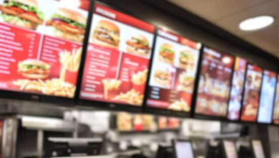 Restaurant menu boards blurred inside a fast-food restaurant.