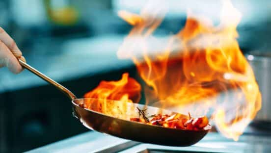 ooks prepare meals on the stove in the kitchen of the restaurant or hotel.
