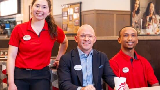 Chick-fil-A CEO Andrew Cathy with two employees inside a restaurant.