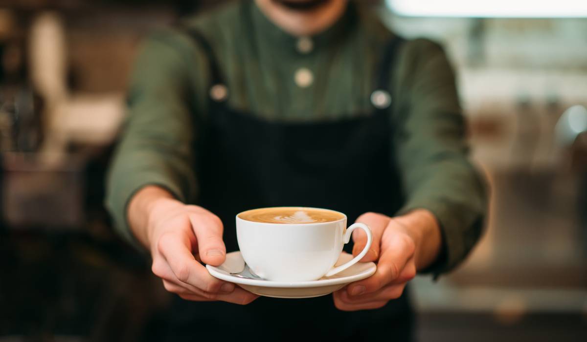Barista holding a cup of coffee.