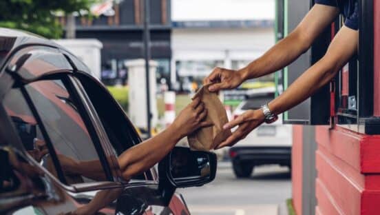 Fast food employee handing food out the drive-thru.
