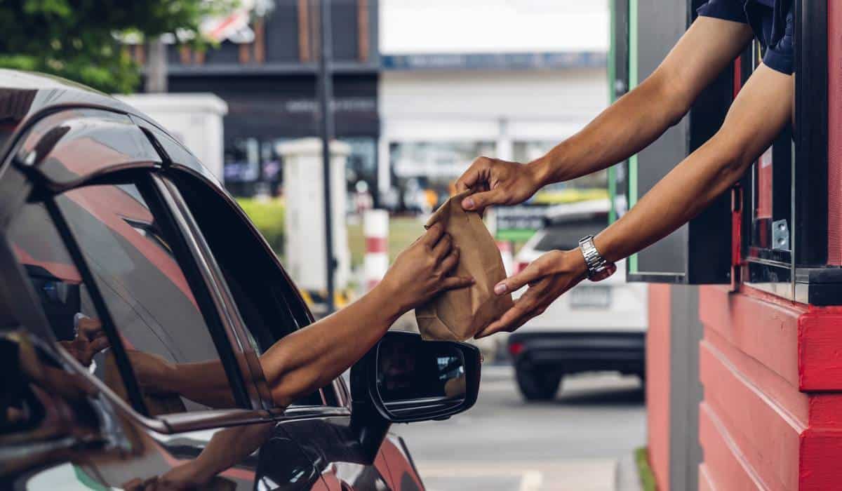 Fast food employee handing food out the drive-thru.