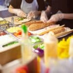 Fast food employees making sandwiches.